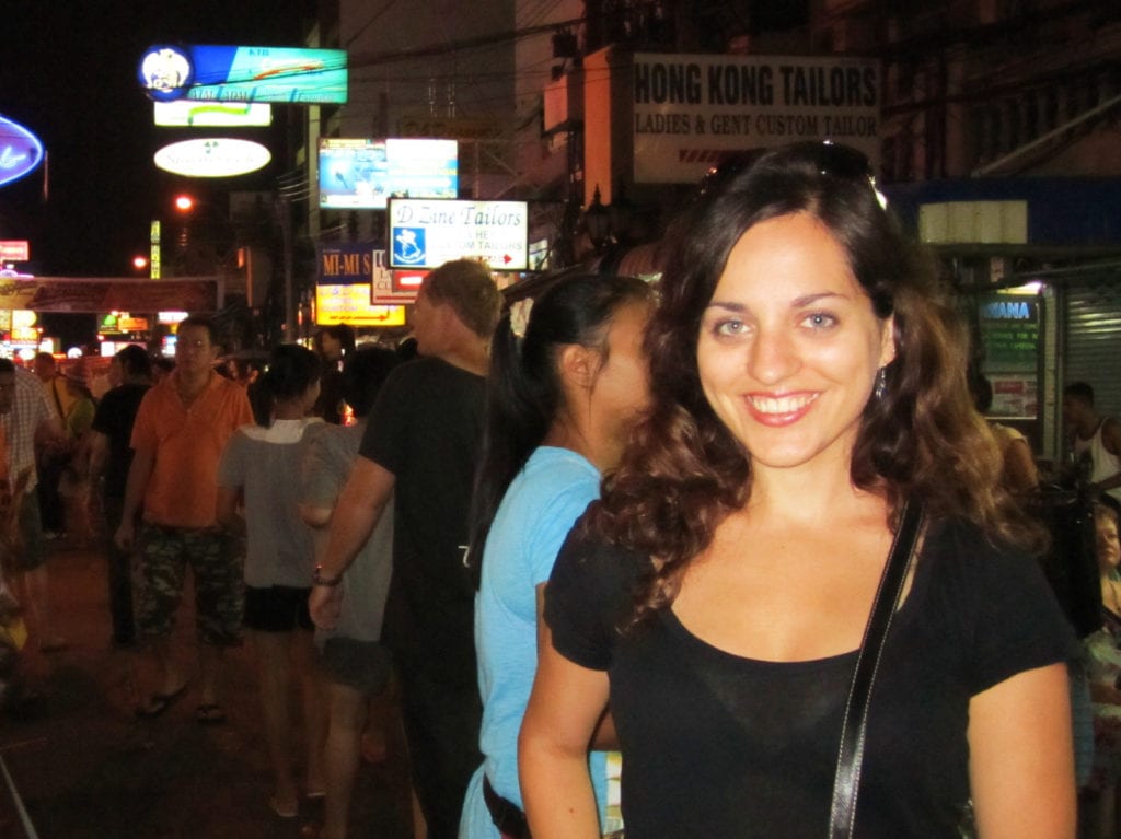 A young-looking 26-year-old Kate stands on Khao San Road in Bangkok, filled with neon signs and crowds. She has a huge smile.