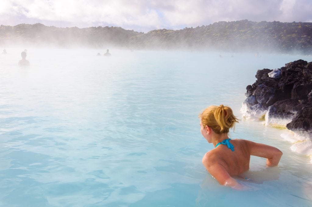 A blonde woman relaxing in the milky blue water of the lagoon.