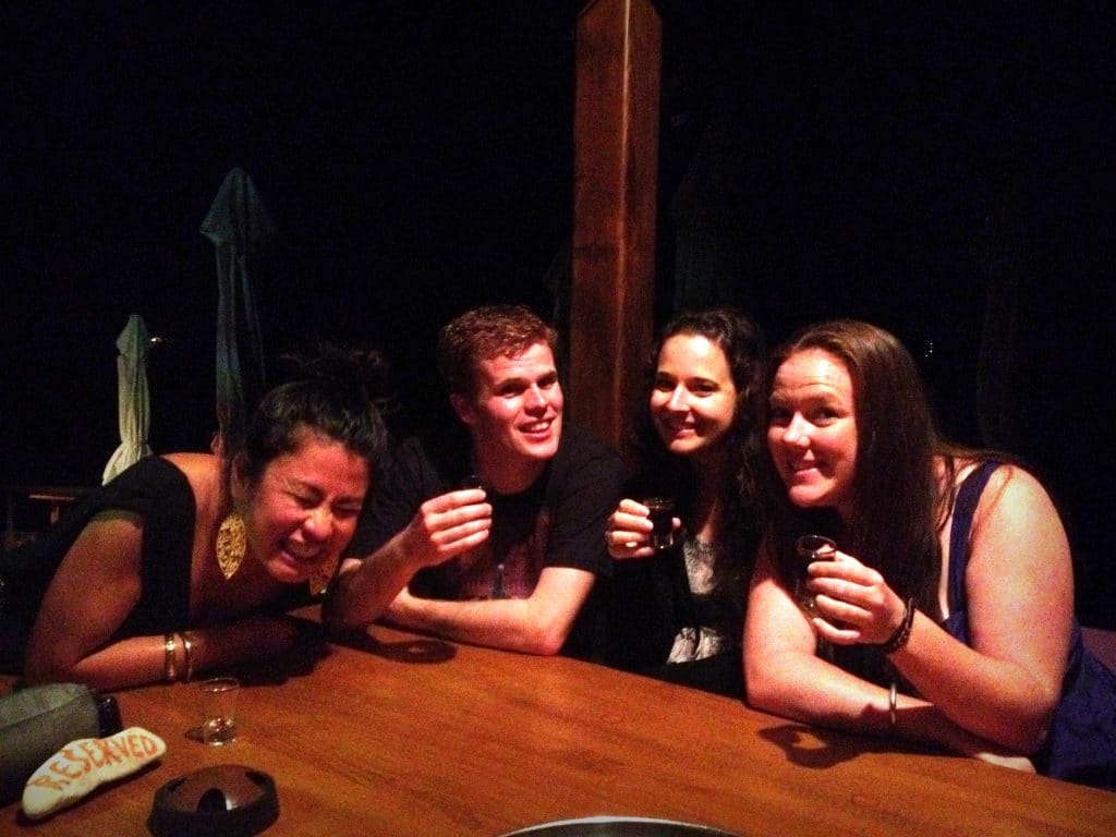 A group of four friends sitting at a table, about to take shots of tequila.