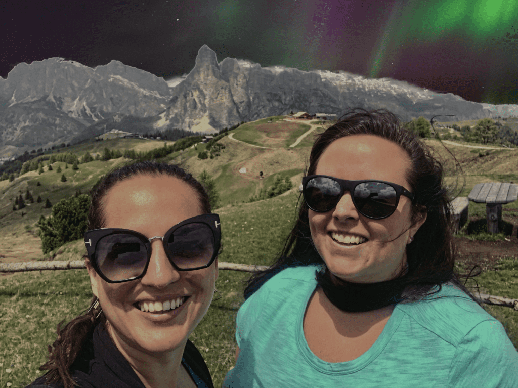 Kate and Cailin standing under a fake Northern Lights view in the Dolomites