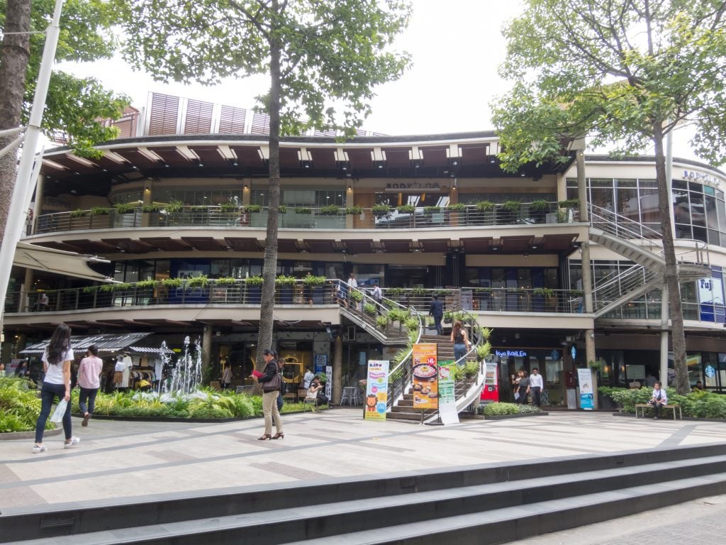 A grassy courtyard in front of a cement, multi-balconied building in Bangkok.