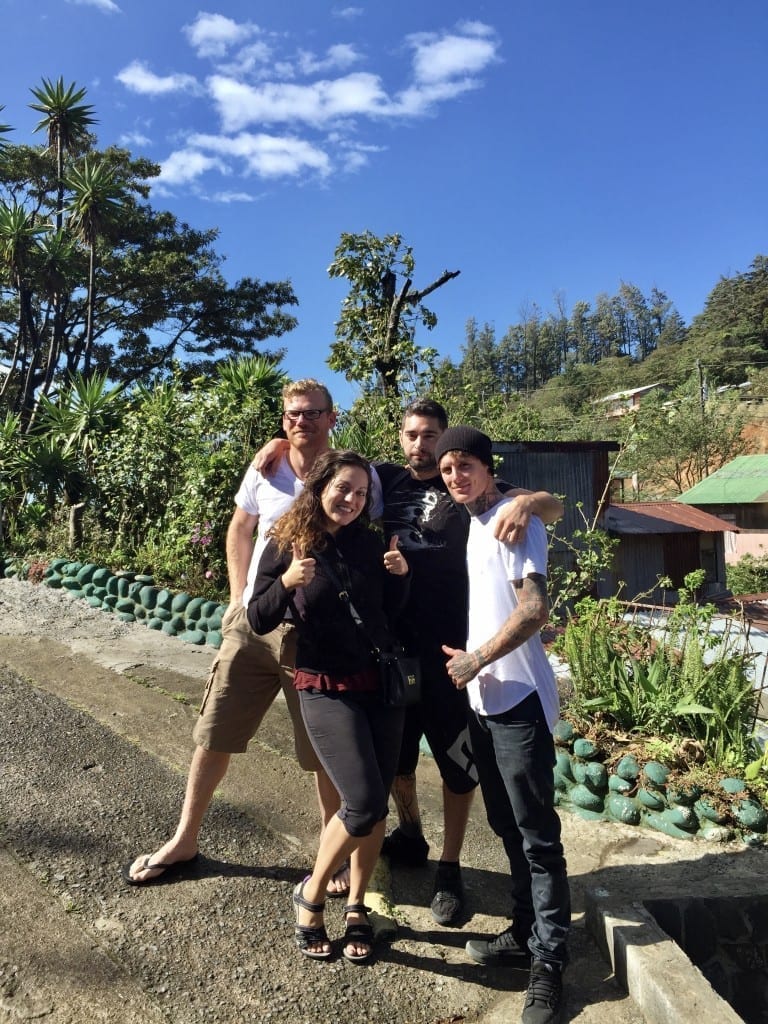 Kate posing with three guy friends on a Costa Rican road, trees and vegetation in the background.