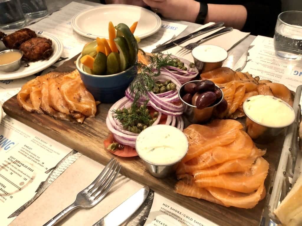 A platter of smoke salmon, onions, capers, tomatoes, and cream cheese.