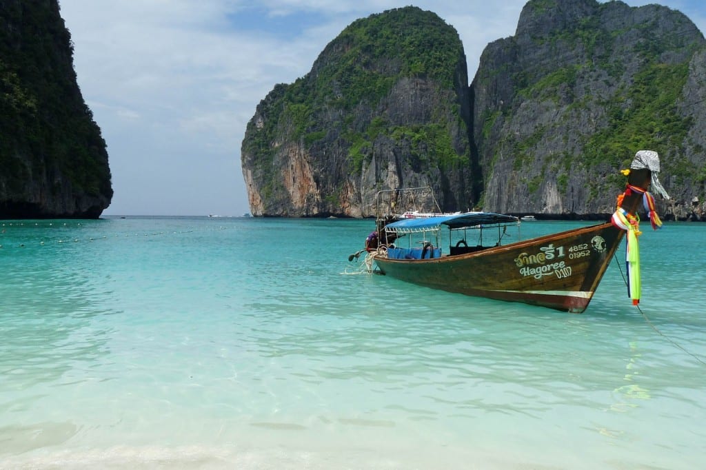 A single Longtail boat on the turquoise water with Koh Phi Phi's cliffs rising around.