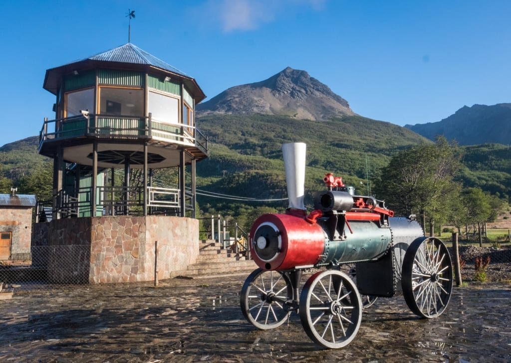 A bright red old-fashioned steam train engine in front of a mountain in Ushuaia.