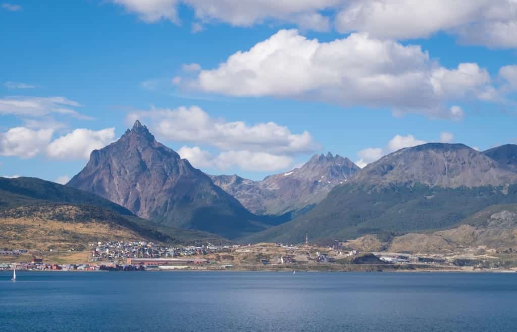 A view of triangular-shaped mountains in front of the still Beagle Channel in Ushuaia.