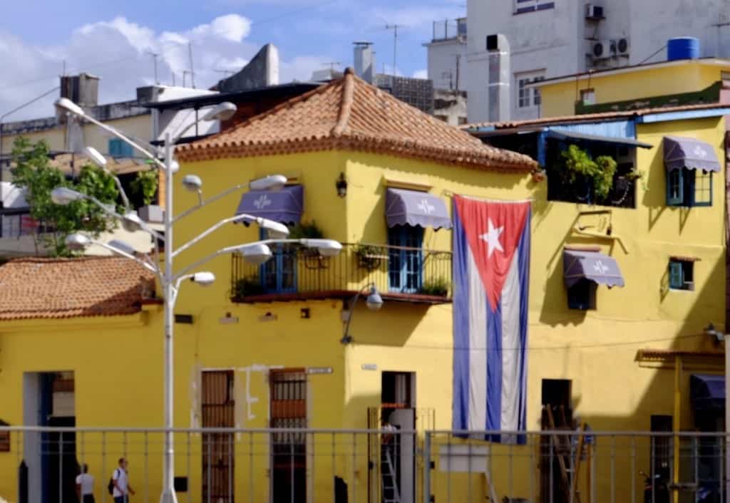 A yellow building with a giant Cuban flag hanging from a window.