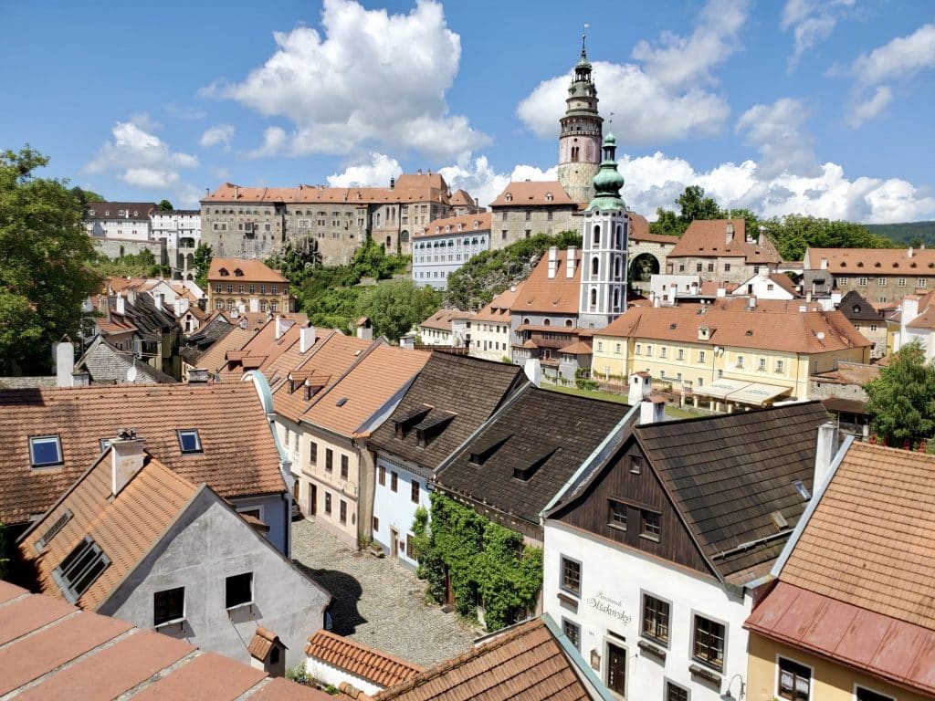 Cesky Krumlov's medieval castle and towers underneath a blue sky with clouds.