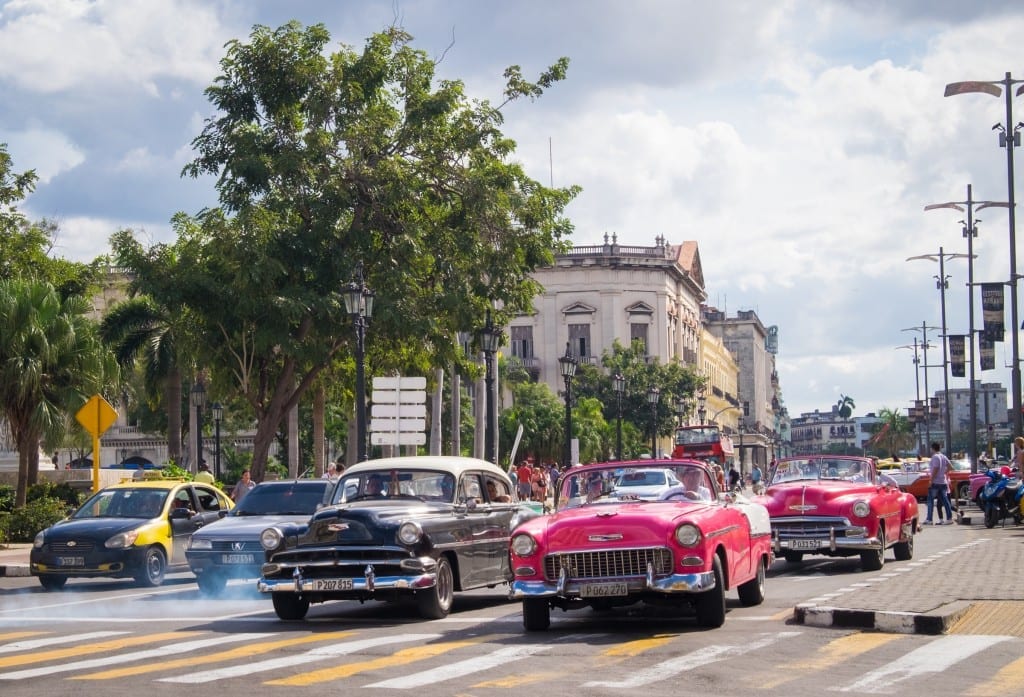 Classic cars at an intersection in Havana, clouds of exhaust behind them.