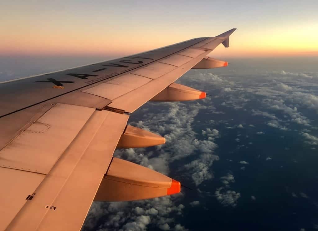 A plane wing at sunset, over a dark cloudy sky.