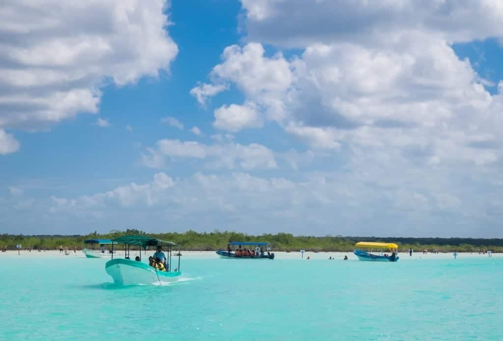 Small speedboats cruising along a turquoise lake.
