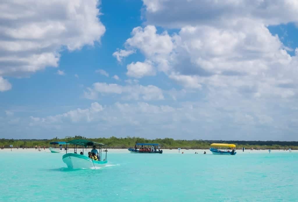 Small speedboats cruising along a turquoise lake.