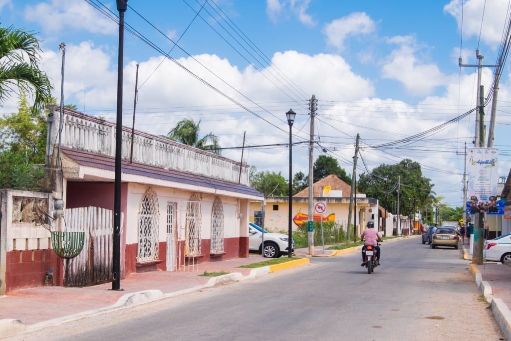 A motorcyclist riding down a street in Bacalar Town.