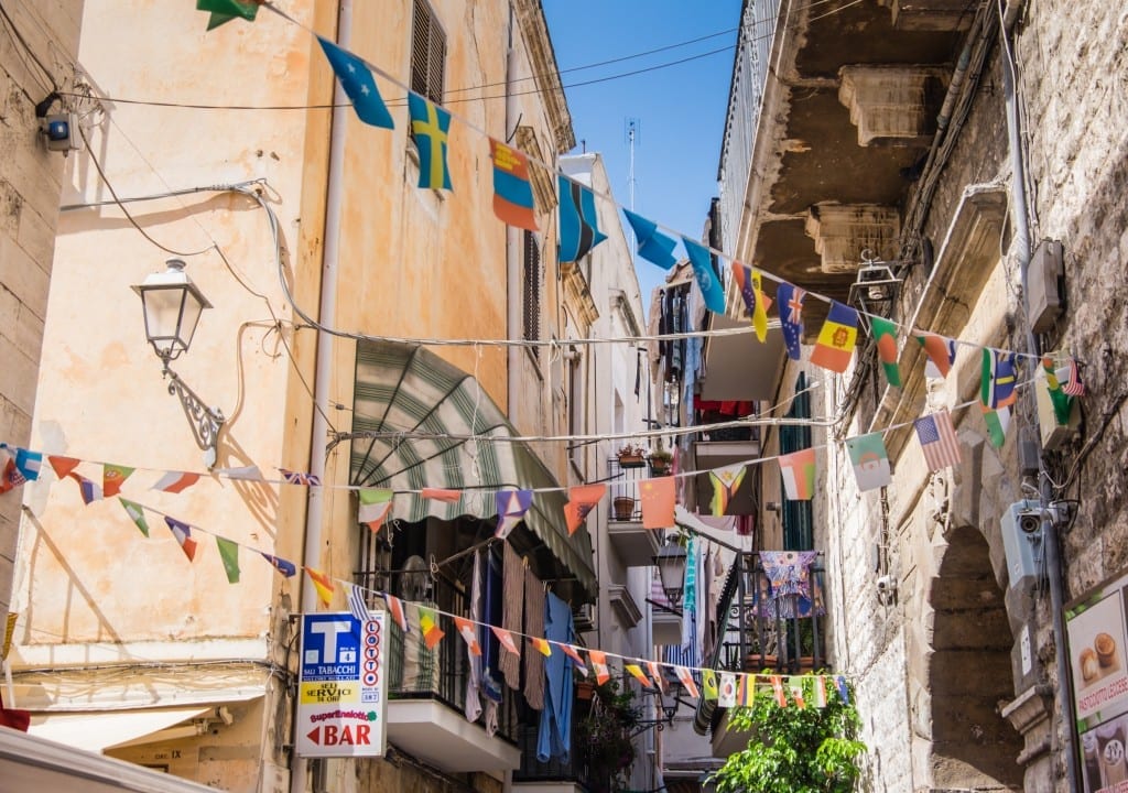 Colorful flags hanging along a narrow alleyway in Old Town Bari, Puglia, Italy.
