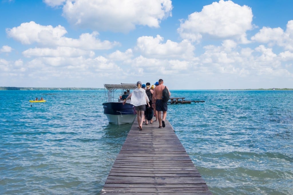 A group of friends walking on a wooden dock to a boat.