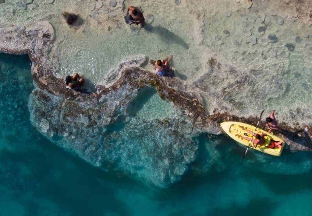 An aerial shot of a person kayaking in clear turquoise waters.