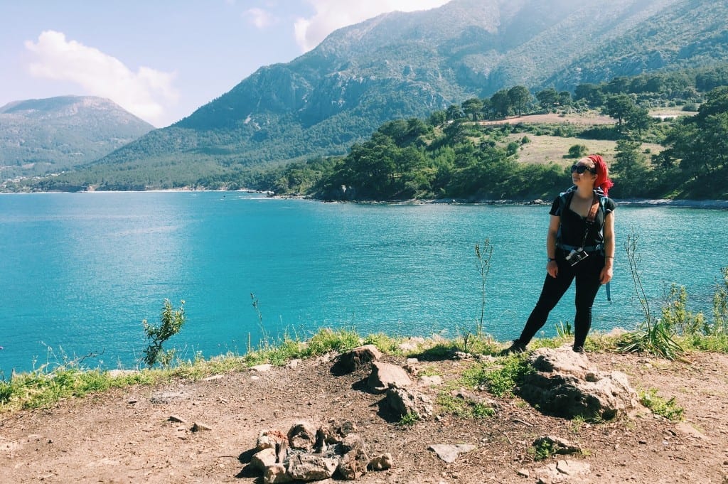 Katie standing on a hiking trail near the teal water of the Mediterranean om the Lycian Way.