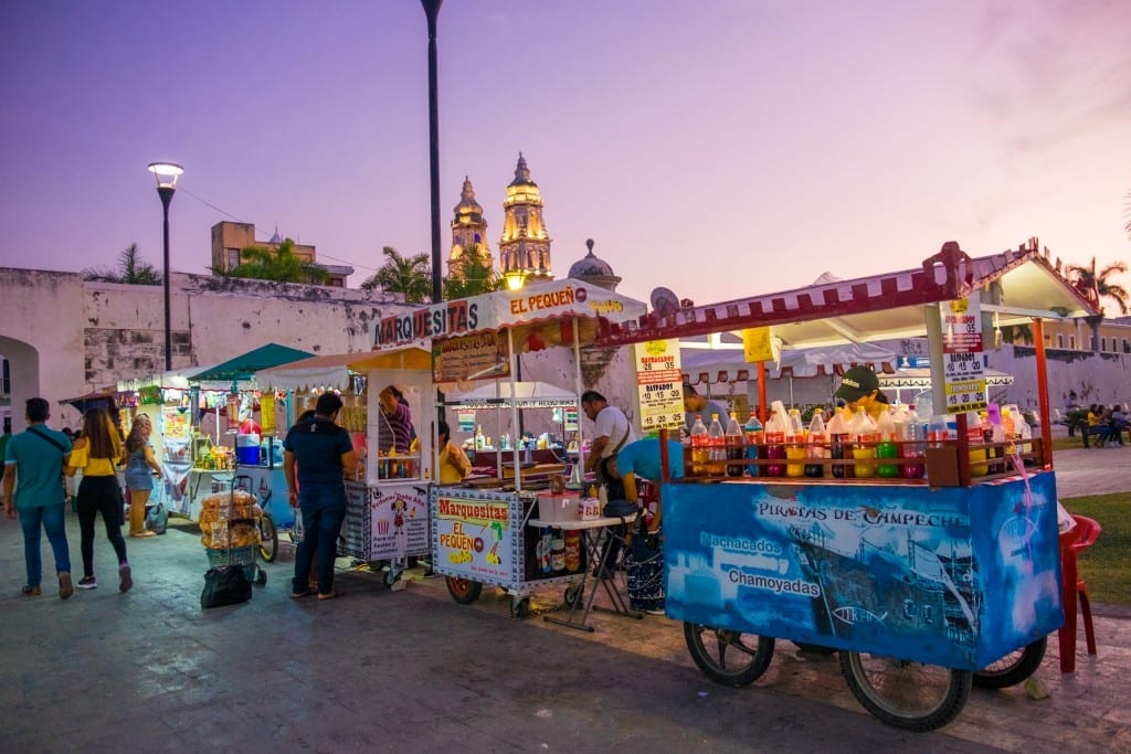 Several street vendors in Campeche, Mexico, serving food under a bright purple sunset.