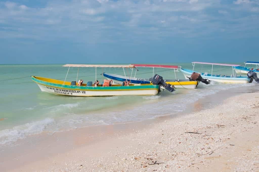 Fishing boats lined up on a white sand beach.