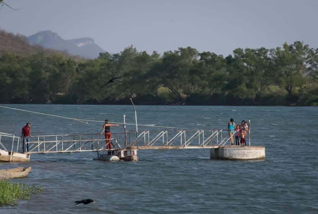 A family taking photos on a metal pier in the river.