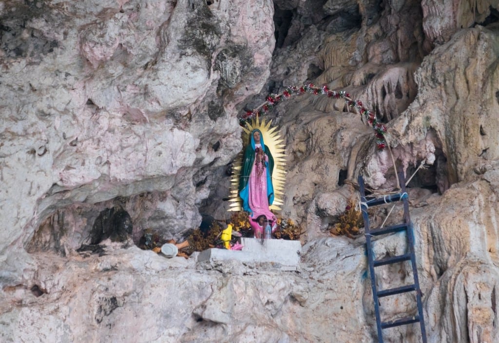 A close-up of the Virgin Mary statue in the cave surrounded by flowers and candles.