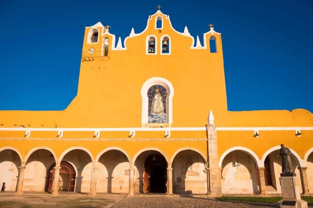 A bright yellow building with a stained glass image of the Virgin Mary.