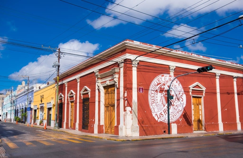 Squat city buildings in Merida: one red, one yellow, one periwinkle blue, one pale blue.