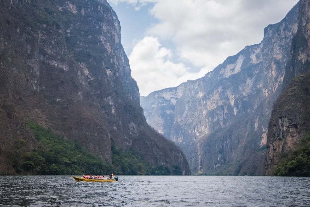 A yellow boat in Sumidero Canyon, surrounded by mountains.