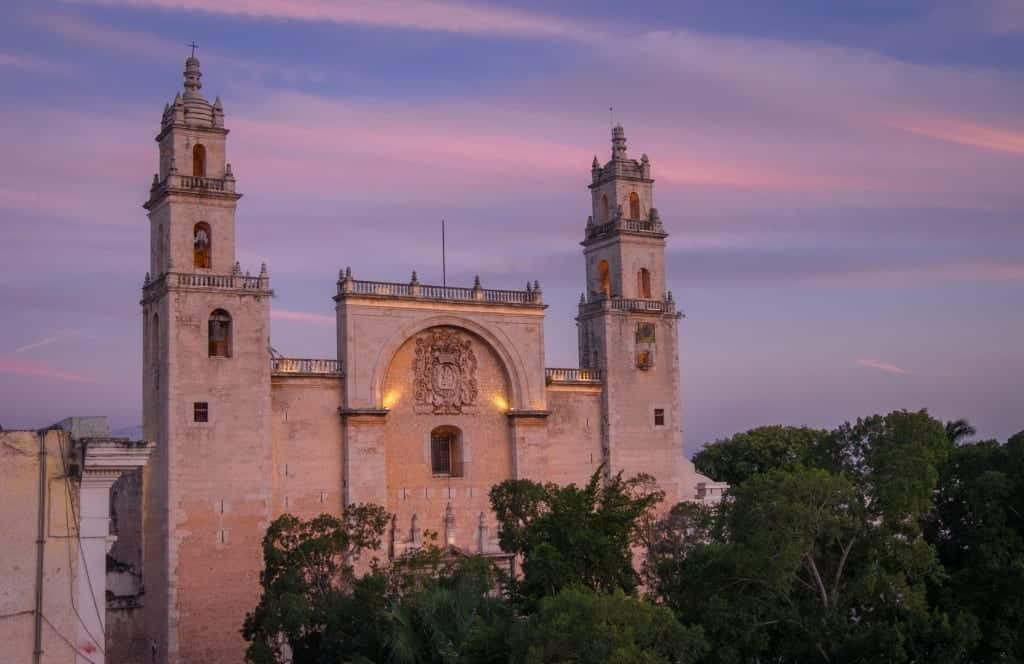 A stone cathedral at sunset with a purple and pink streaked sky behind it. 