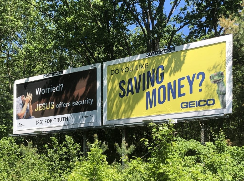 Two billboard ads: one says "Worried? Jesus offers security." Other says "Do you like saving money? GEICO."