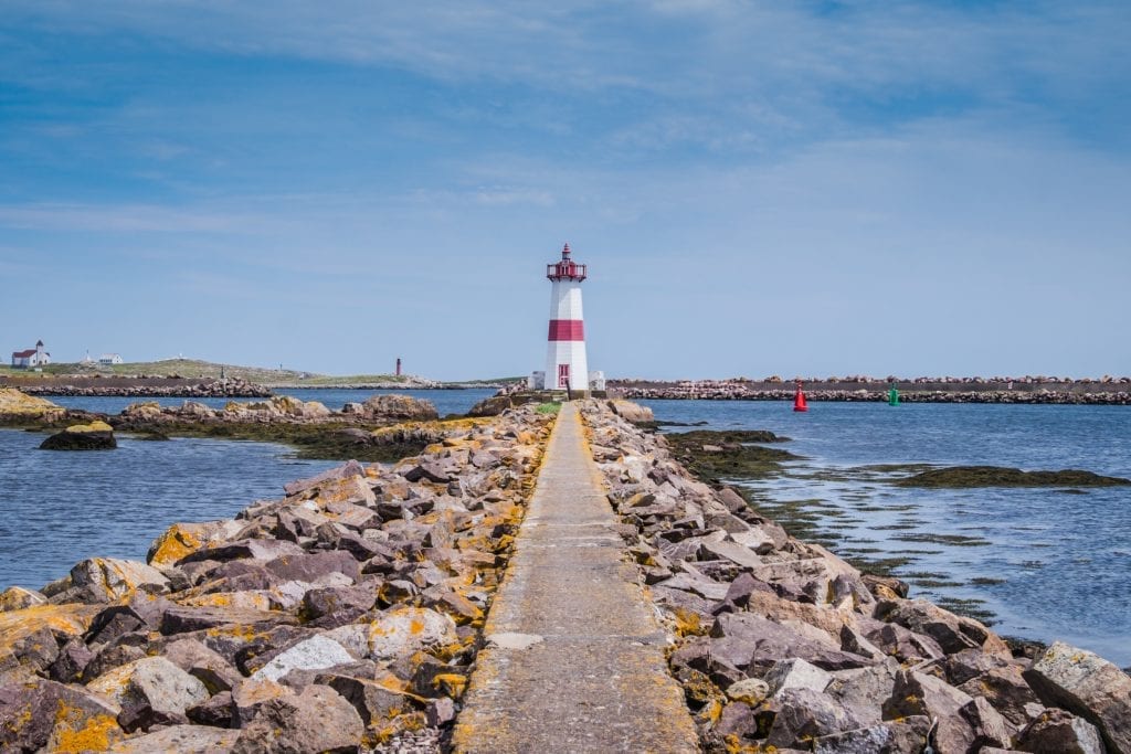 A rocky path leading to a red and white lighthouse.