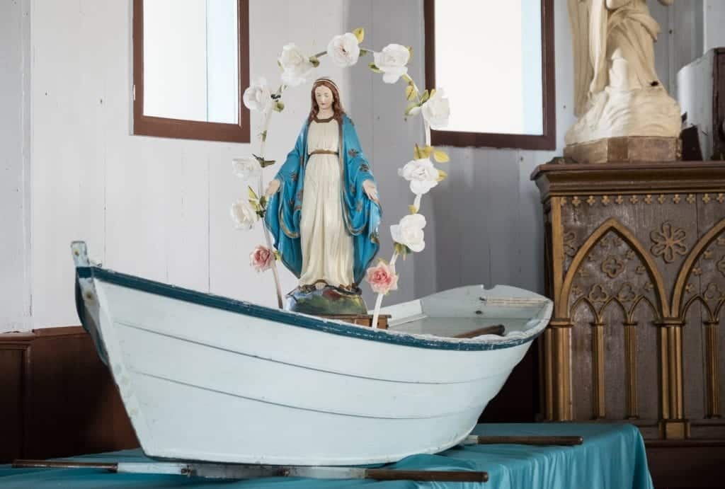 A Virgin Mary placed inside a wooden rowboat, on display in a church.