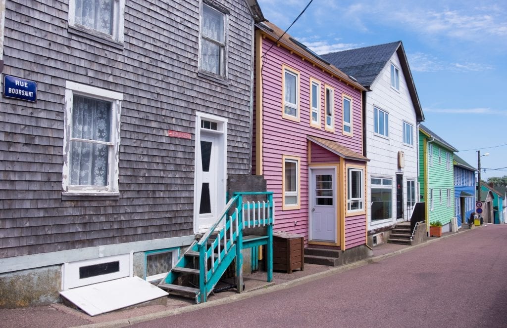 Weatherbeaten gray, purple, white, and green homes on a street in St. Pierre labeled Rue Boursaint.