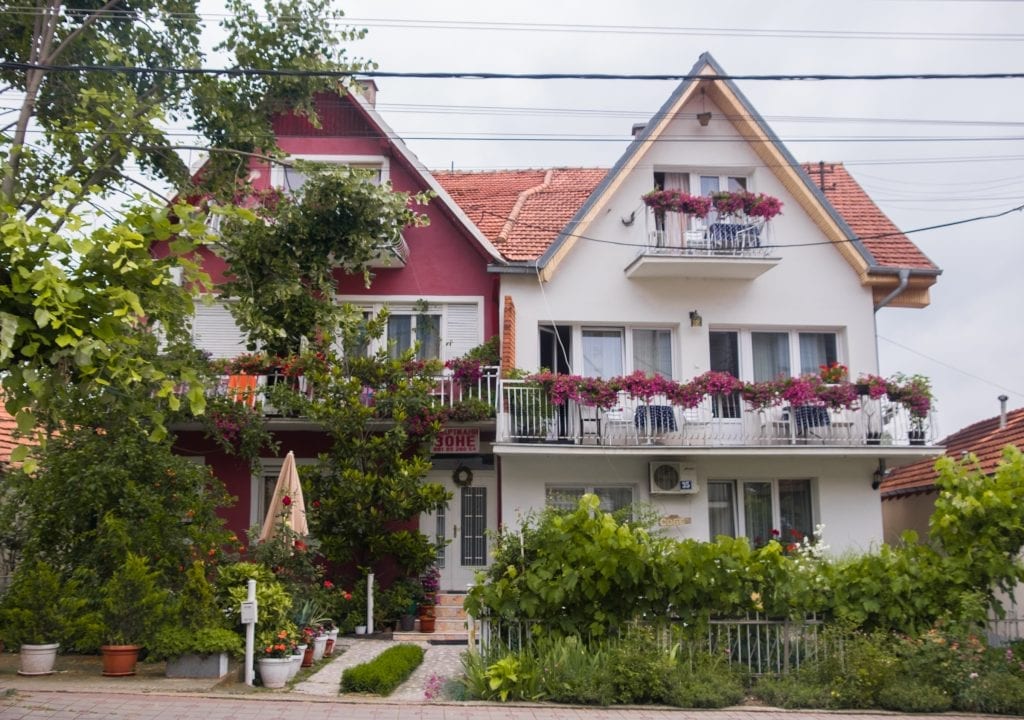 Two houses in Sokobanja decorated with garlands of purple flowers.