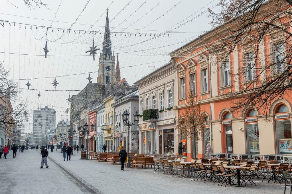 Colorful buildings and street cafes in Novi Sad, Serbia, leaving to a church.