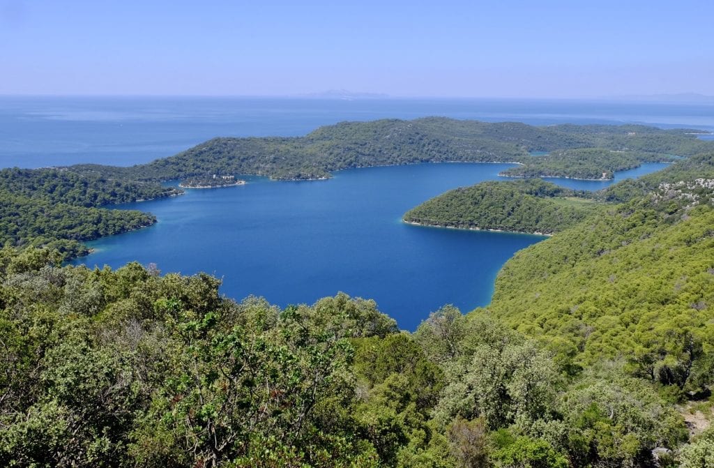 The view from above Mljet, an island covered with lush green trees, and in the center, a bright blue saltwater lake.