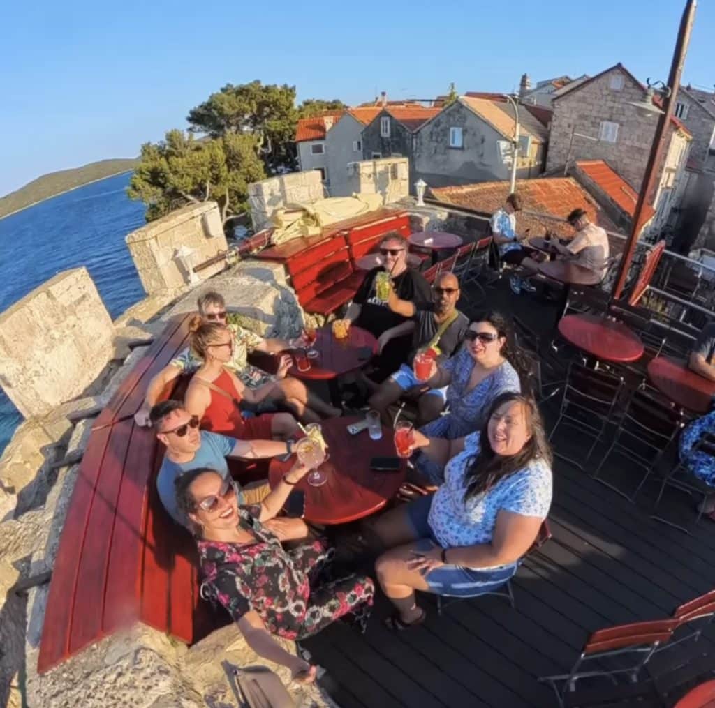 A group of friends toasting cocktails on the tower of a city wall.
