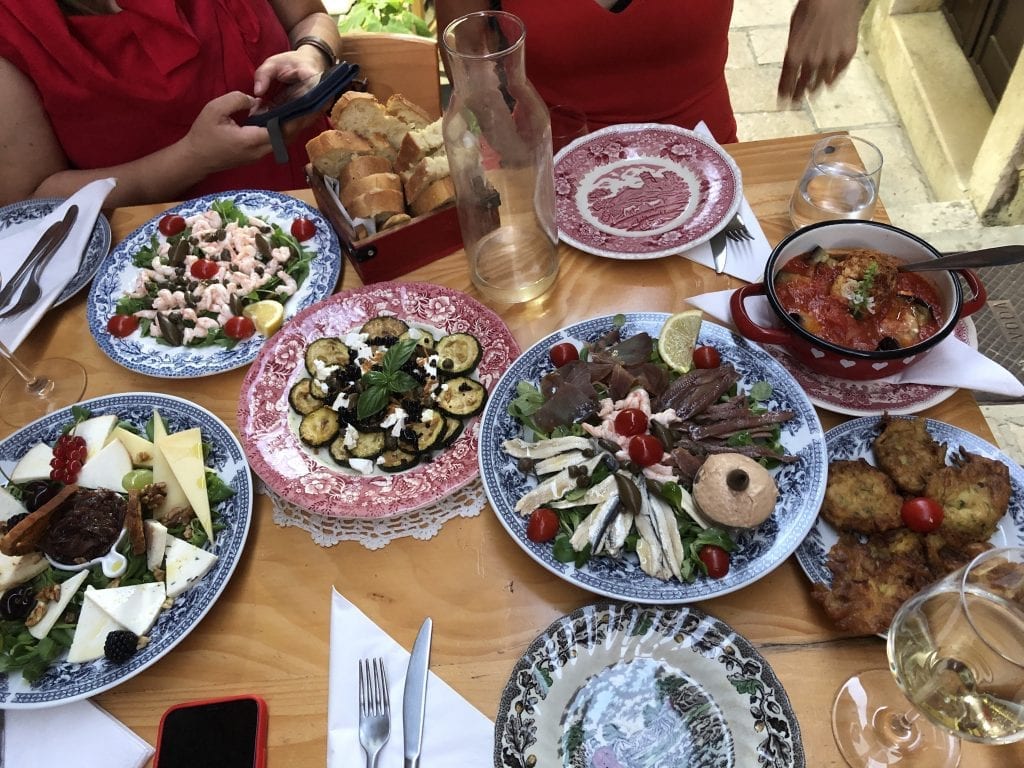 Small plates filled with lots of different apps along with wine glasses on a table in Korcula.