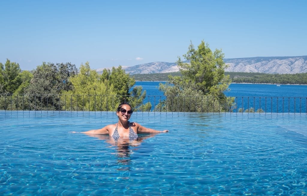 Kate lounging in an infinity pool overlooking the forest and the sea in Hvar.