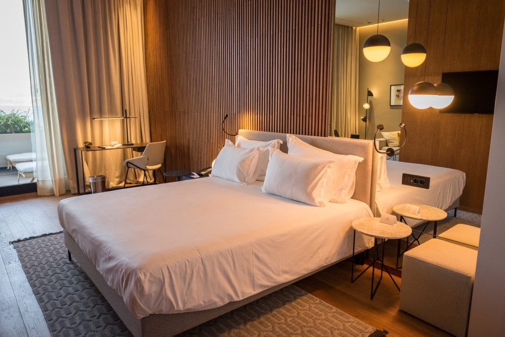 Bed with white linens and pillows with a desk and chair in the background at Hotel Dubrovnik Palace