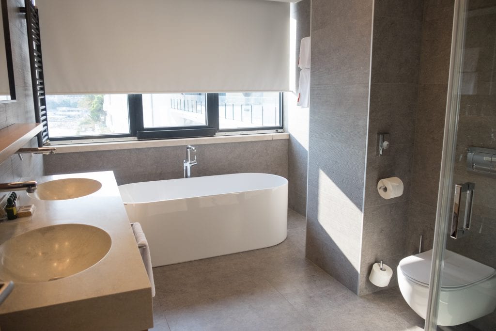 Bathroom at Hotel Excelsior with modern white tub, two sinks and a toilet