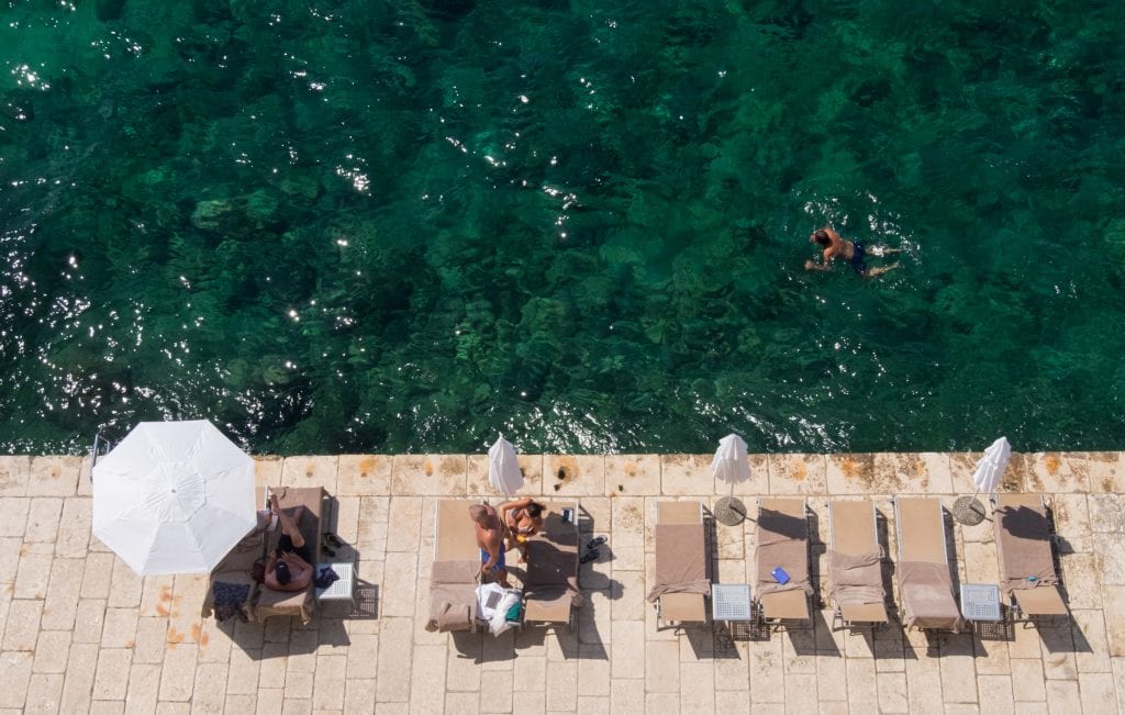 Aerial view of beach chairs lined up along a cobblestone boardwalk that drops into the ocean