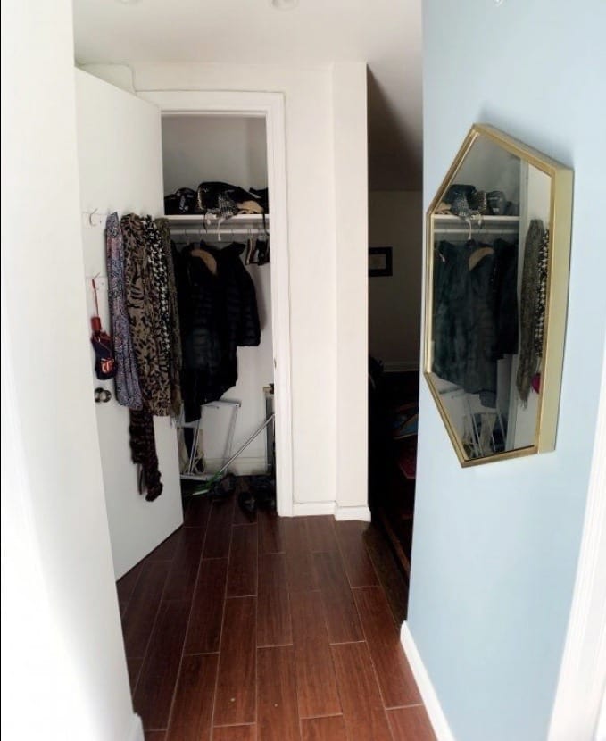 Kate's hallway leading to a closet with scarves hanging on the open door, and a gold hexagonal mirror on the right wall.