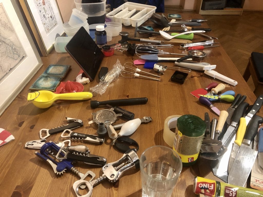 A table filled with miscellaneous kitchen tools: corkscrews, beaters, knives, all grouped by category.