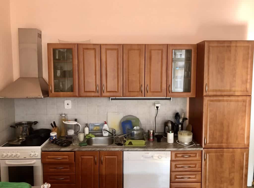 Close up on the kitchen cabinets, including a small stove, small sink, and dishwasher.