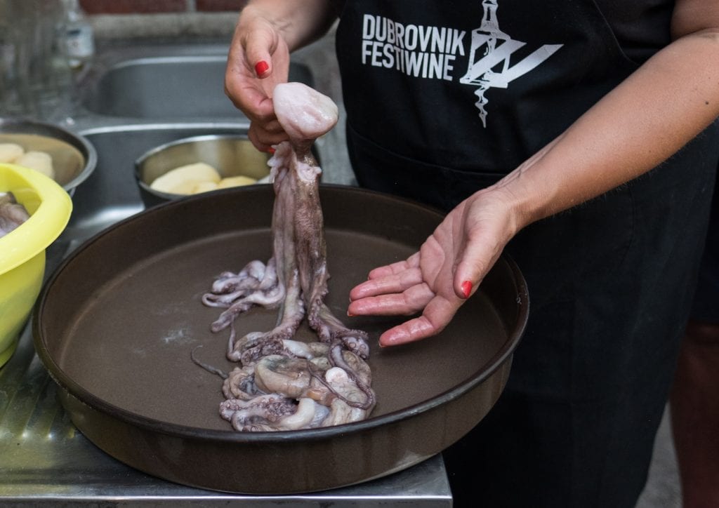 A woman holds octopus in her hands over a black platter