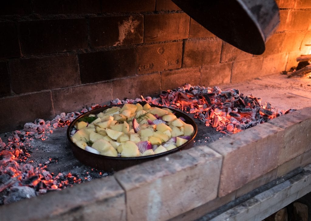 Peka, a Croatian meal cooked over coals, is placed in a brick oven and surrounded by coals