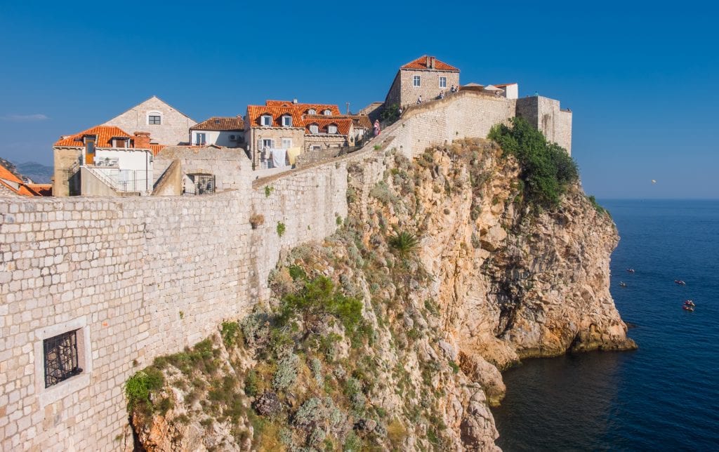 Outer wall of Dubrovnik's Old City with a tall rock face that falls into the ocean