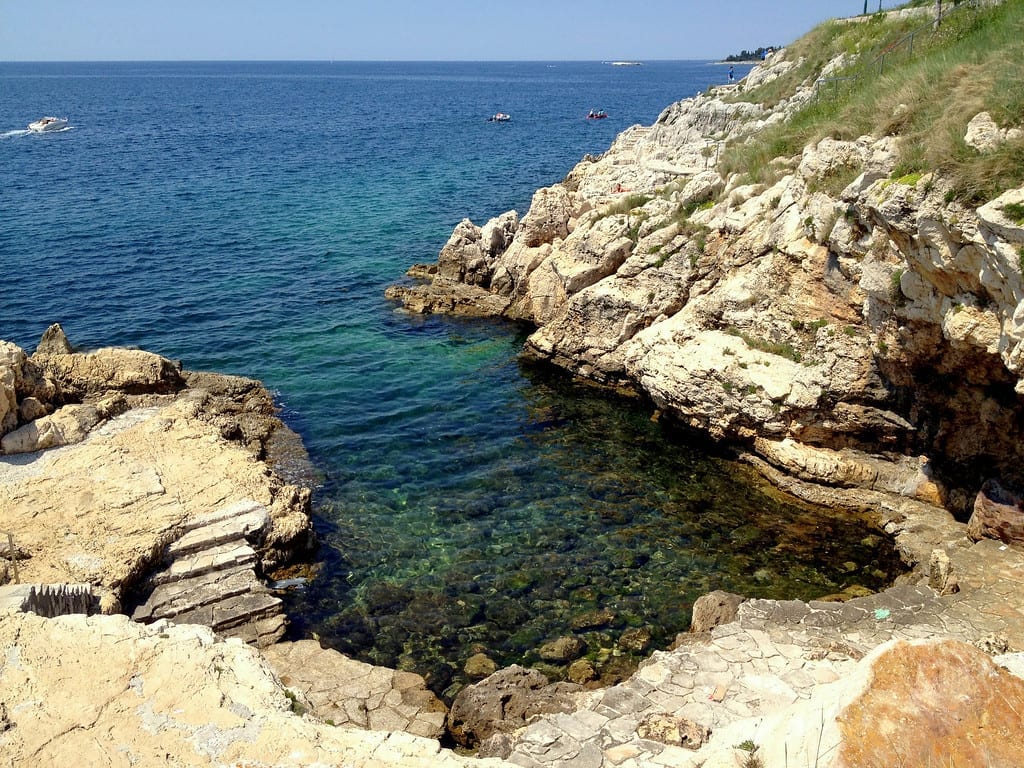 A small rocky bay with clear teal water in Rovinj.