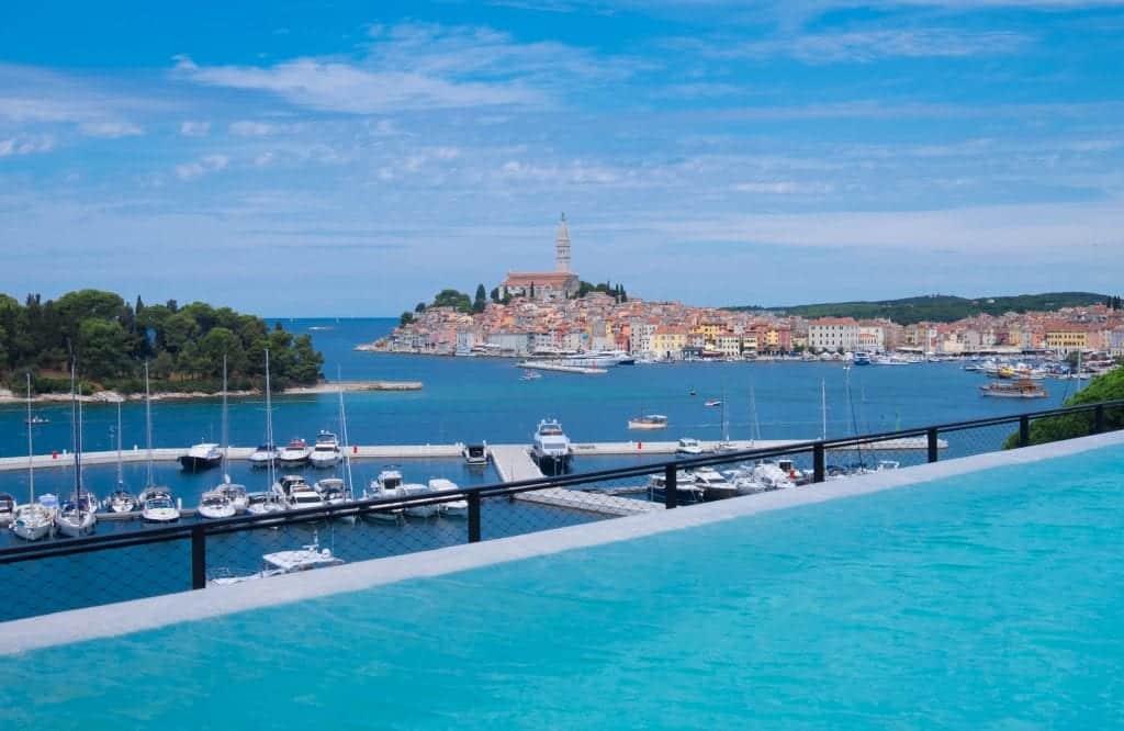 The view of the city of Rovinj with a bright blue infinity pool in the foreground.